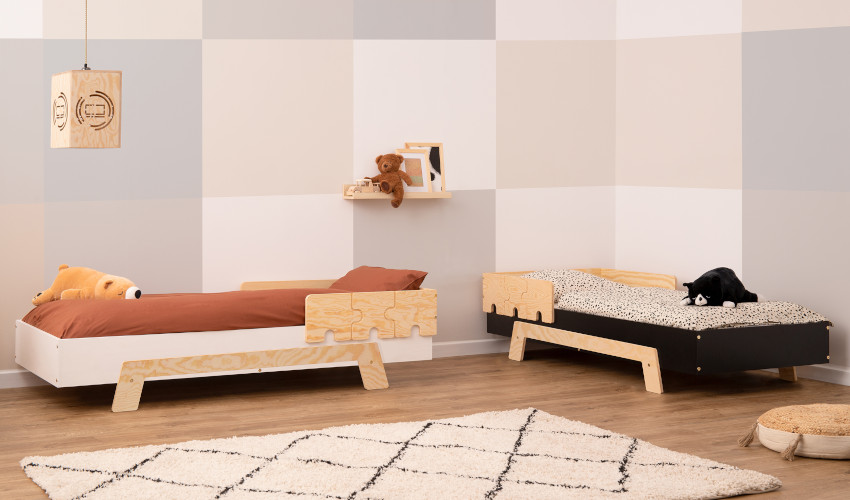 Białe i czarne drewniane łóżko z barierką w kształcie puzzli wykonaną ze sklejki sosnowej w kolorze naturalnego drewna